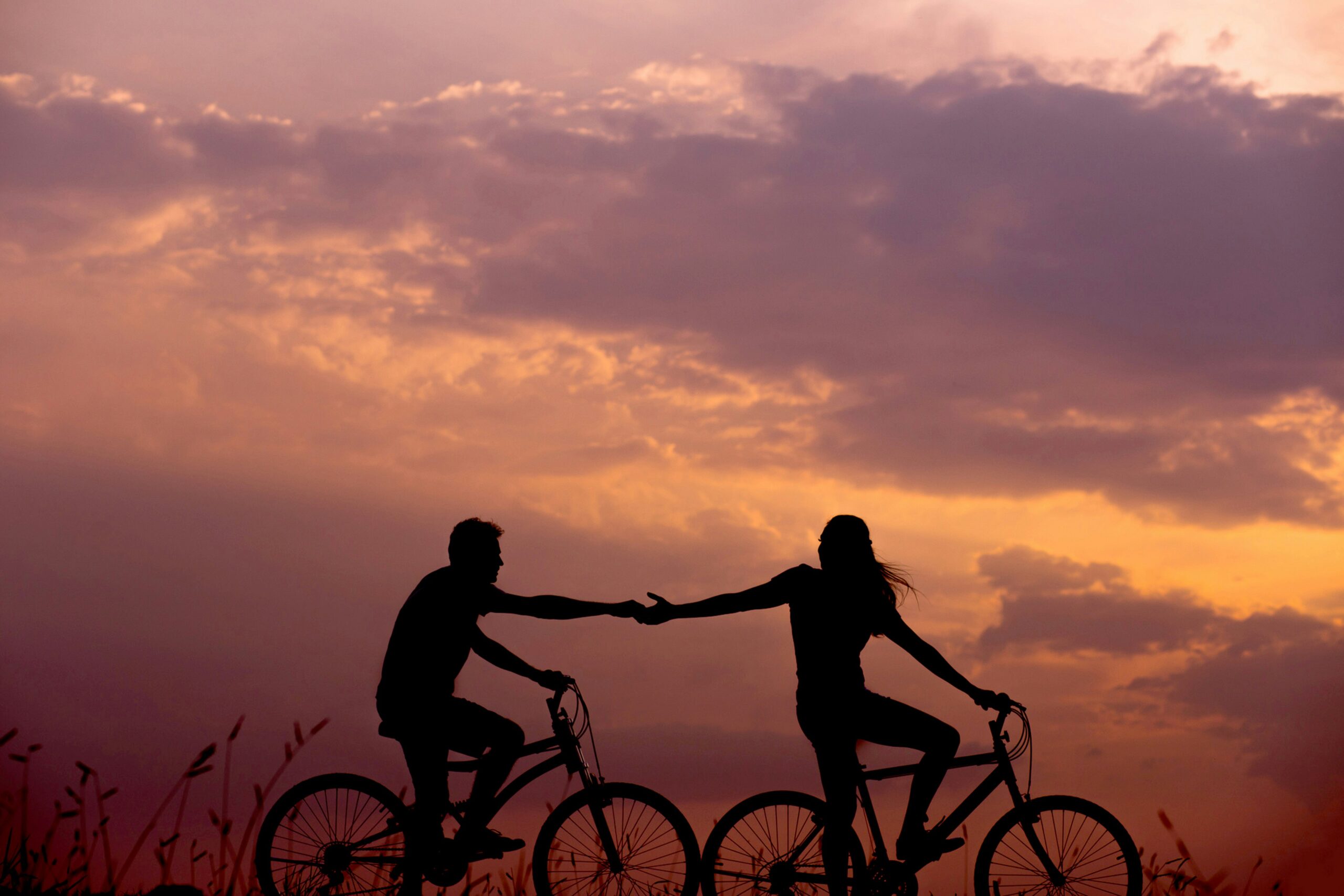 couple holding hands while biking for a date night